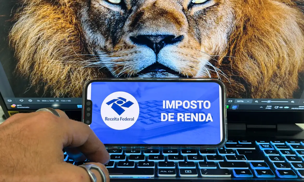 Celular exibe tela do Imposto de Renda da Receita Federal sobre teclado de notebook