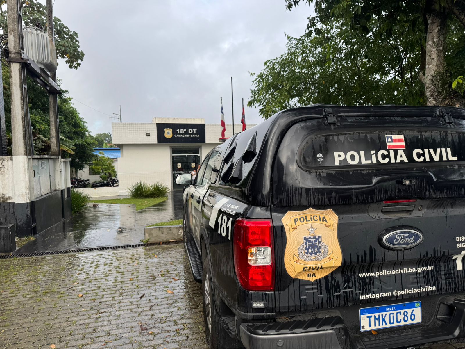 Viatura da Polícia Civil em frente à 18ª Delegacia Territorial de Camaçari durante ação relacionada à prisão por violência doméstica.