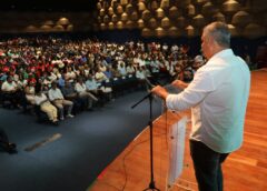 Participantes acompanham evento da agricultura familiar em auditório durante discurso em palco na Bahia.
