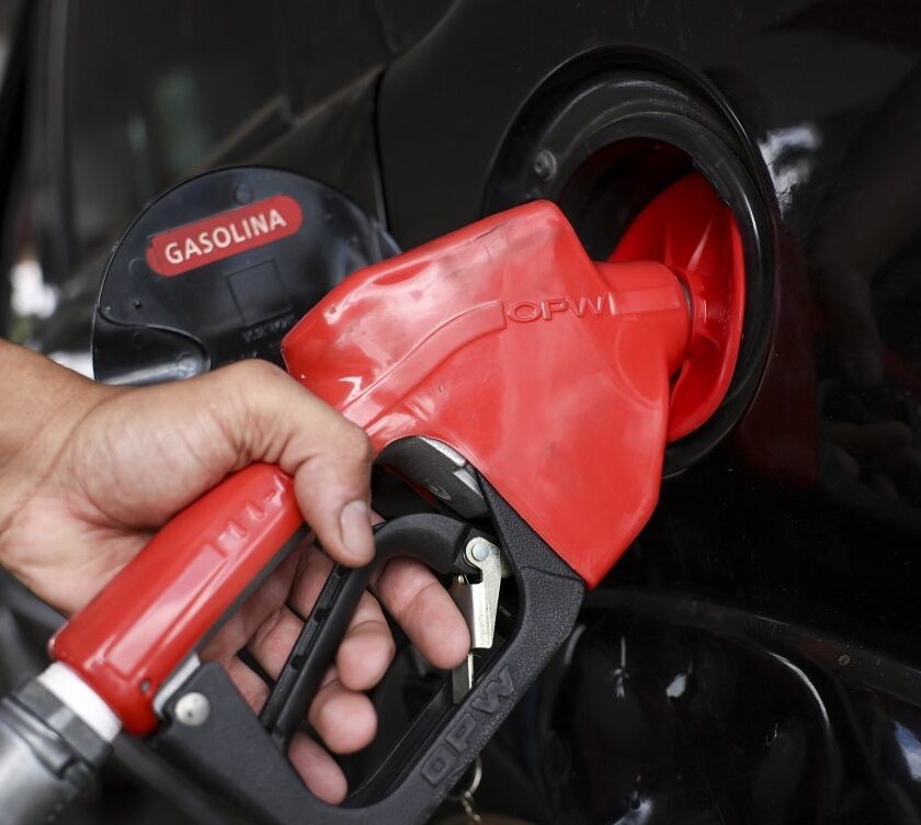 Bico de abastecimento de gasolina em veículo durante abastecimento após redução no preço da gasolina anunciada pela Acelen.