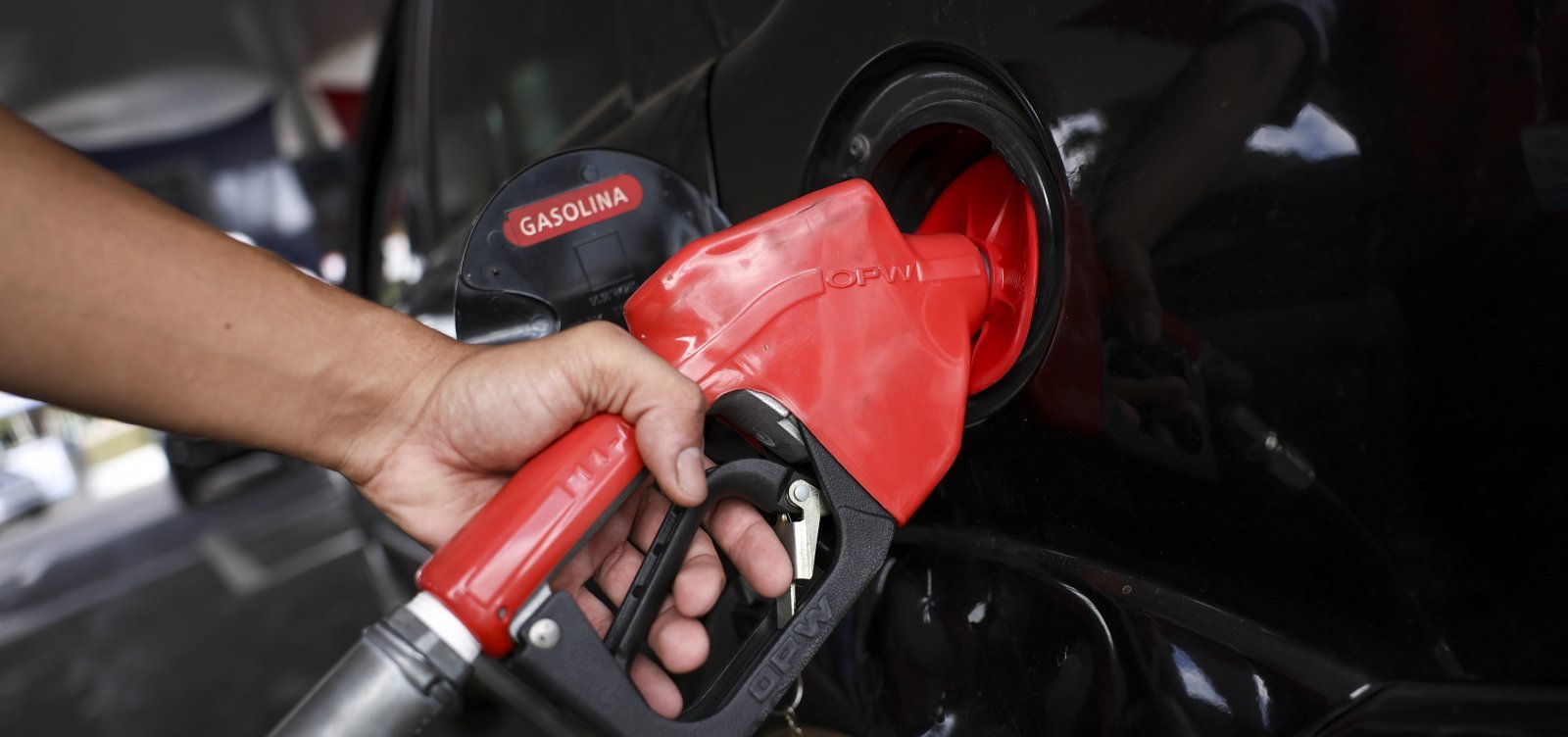 Bico de abastecimento de gasolina em veículo durante abastecimento após redução no preço da gasolina anunciada pela Acelen.