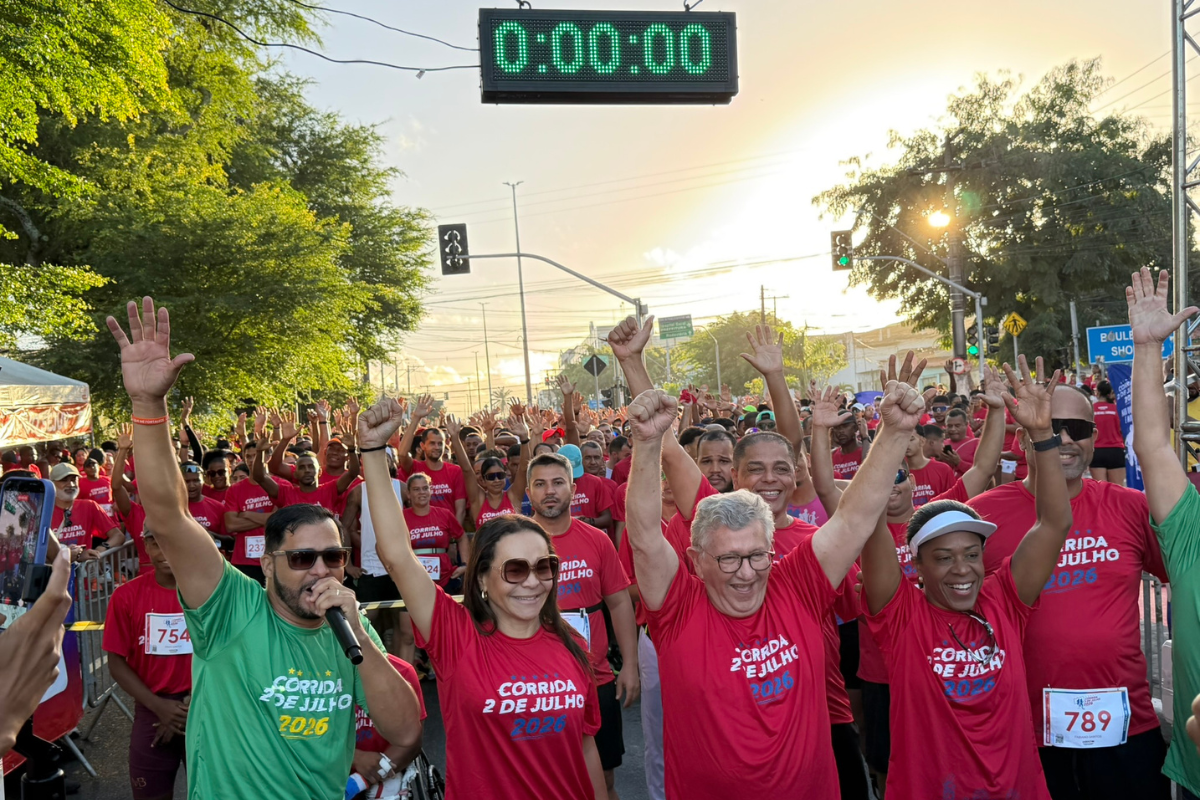 Participantes da Corrida 2 de Julho 2026 celebram a largada do evento em Camaçari, com centenas de corredores reunidos na avenida durante as comemorações da Independência da Bahia.